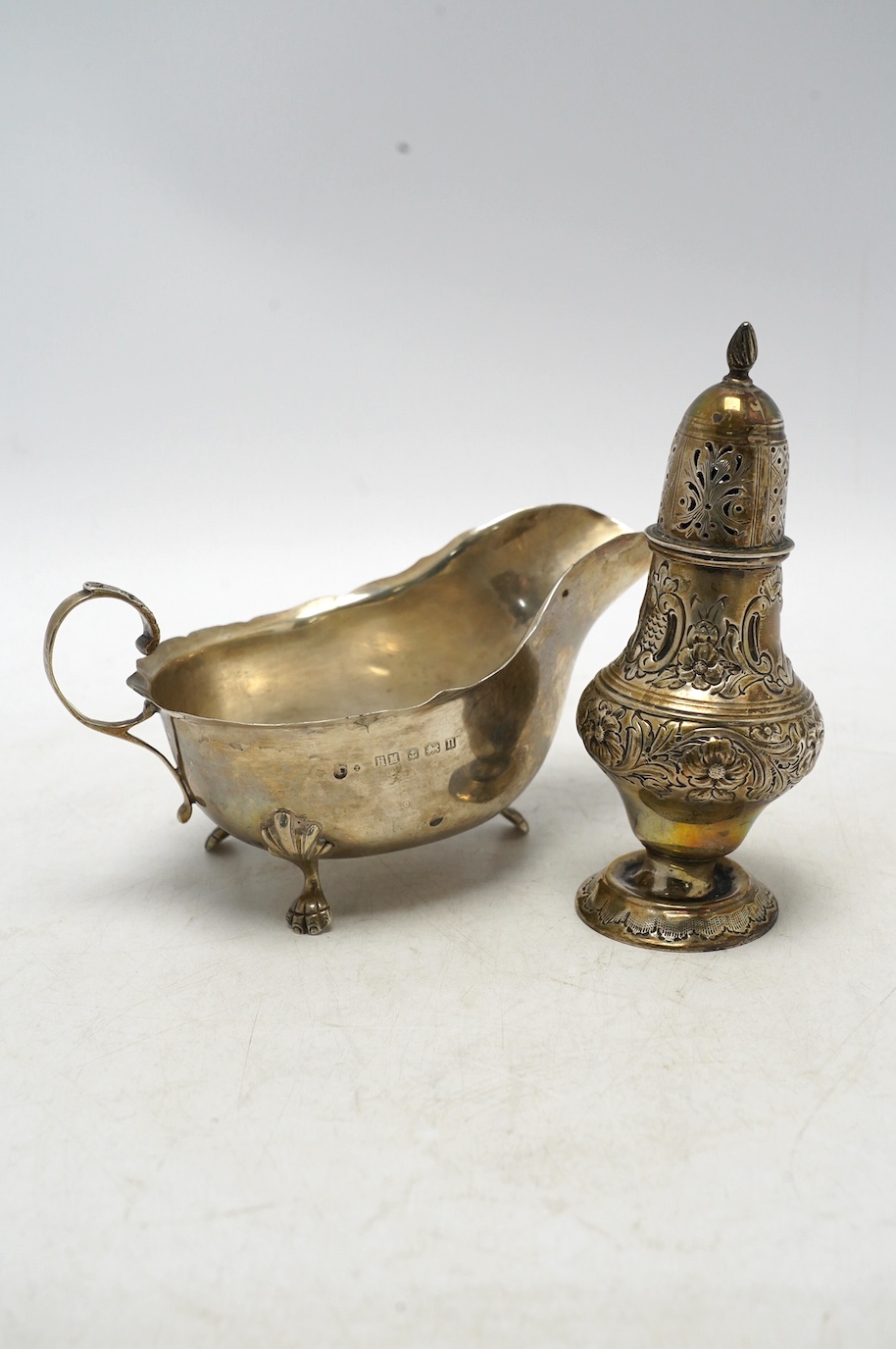 A late Victorian repousse silver pedestal sugar caster, Birmingham, 1893, 14.2cm, together with a later silver sauceboat, 6.6oz. Condition - poor to fair